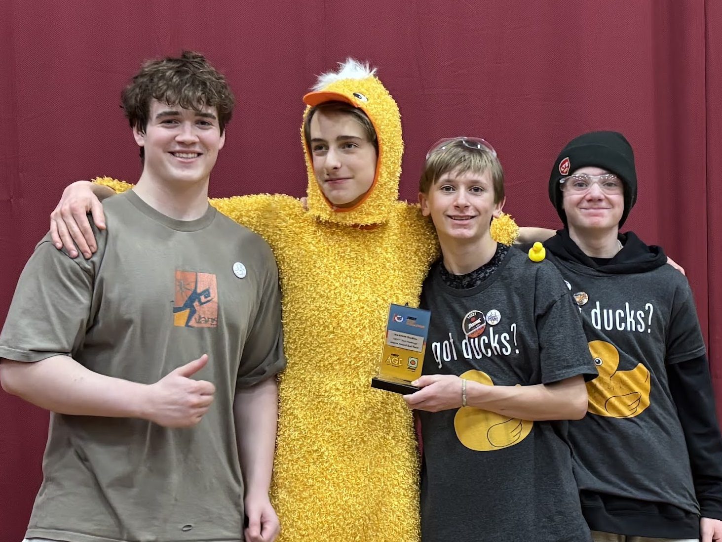 Zach, Miles (in full duck costume), Ben, and Liam with their Inspire Award runner-up trophy at the Norwich Qualifier